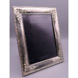A Carrs silver rectangular silver photograph frame embossed with flowers and foliage. 17 x 22 cm.