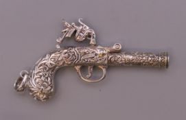 A silver gun form pendant. 7 cm long.