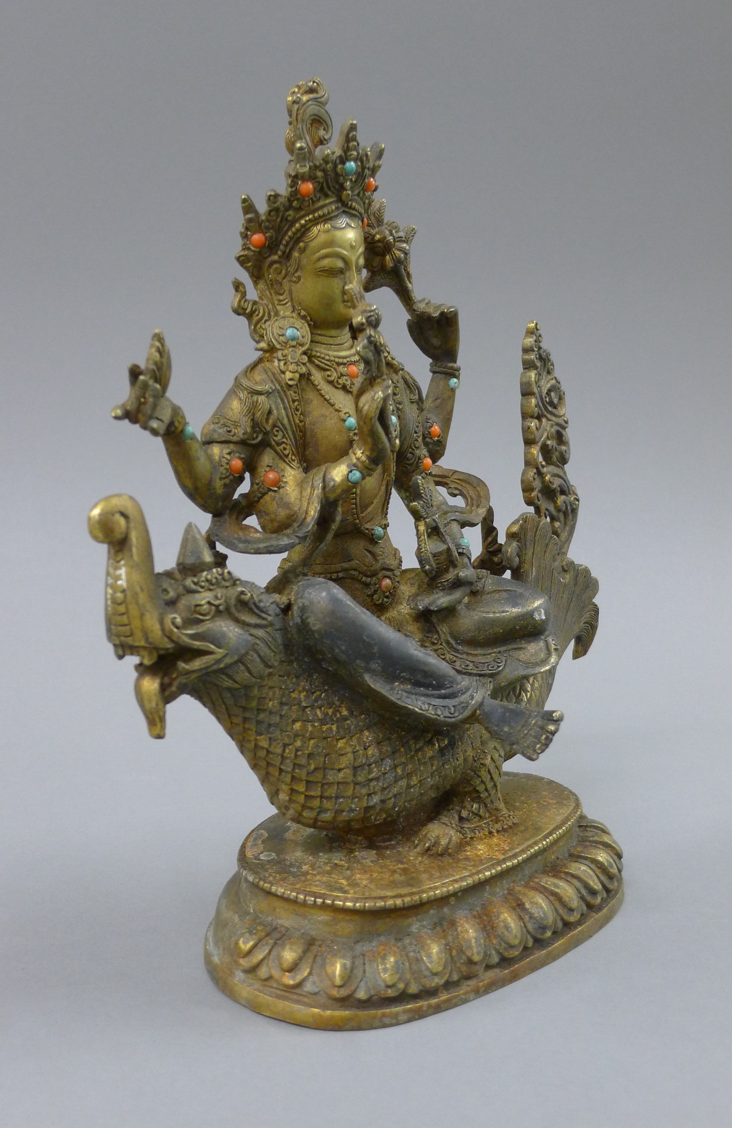 A gilt bronze model of Buddha decorated with coral and turquoise, seated on a mythical beast. 25. - Image 2 of 4