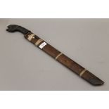 A Javanese Wedung knife with carved head horn handle and wooden sheath. 62 cm long.