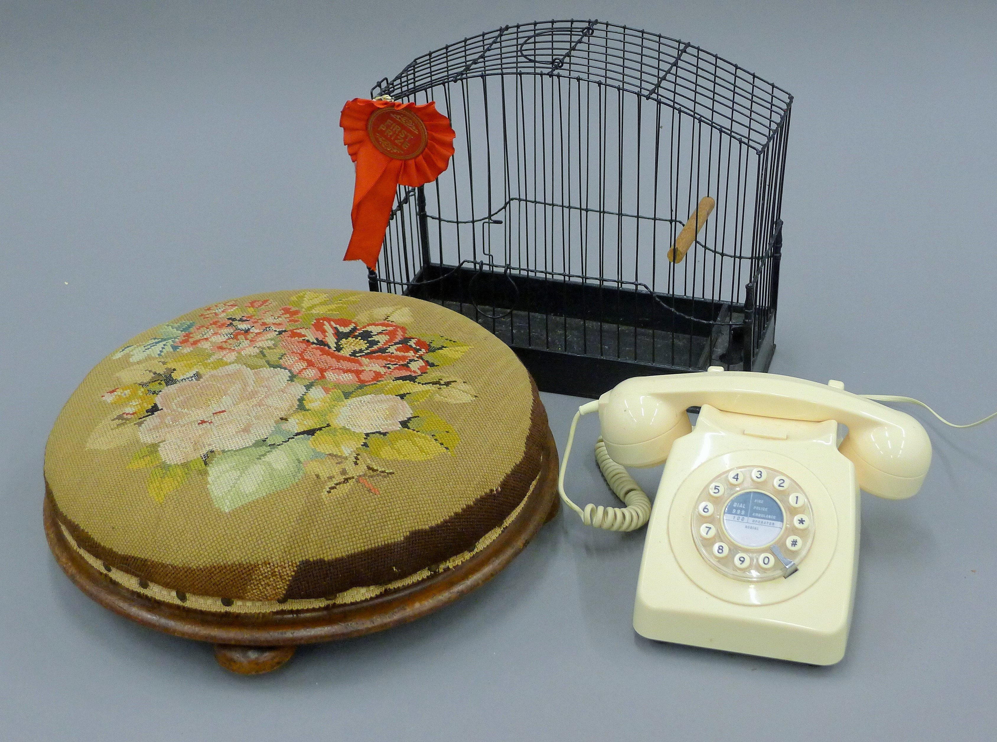 A Victorian stool, a vintage bird cage and a white telephone.