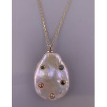 A stone set mother-of-pearl pendant mounted on a silver gilt chain. The pendant 2.5 cm high.
