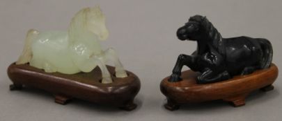 Two Chinese hardstone recumbent horses on wooden bases. The largest 10 cm long overall.