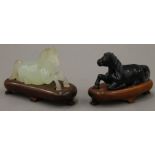 Two Chinese hardstone recumbent horses on wooden bases. The largest 10 cm long overall.