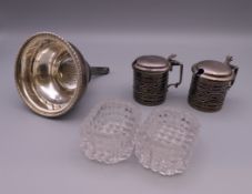 A pair of silver mustard pots, a silver wine funnel and a pair of glass salts.