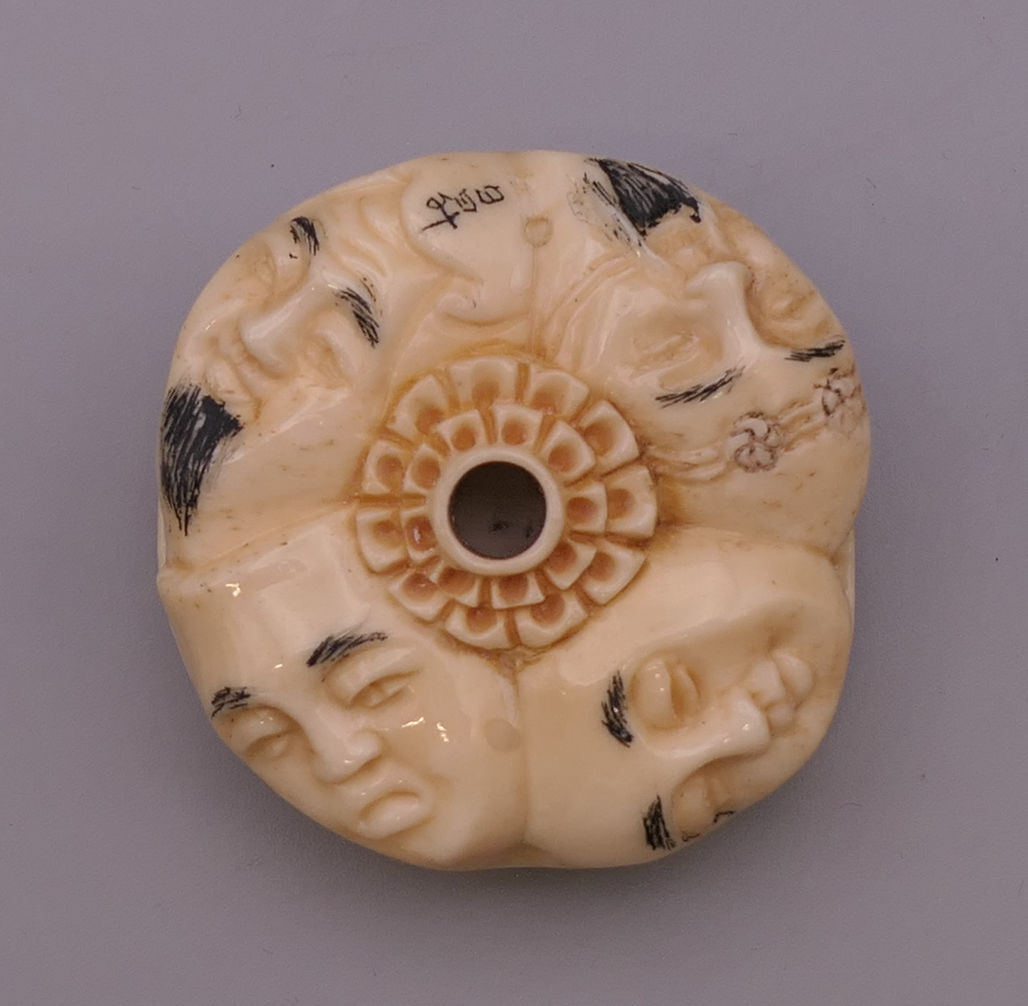 A bone toggle carved with faces. 4 cm diameter. - Image 2 of 5