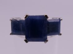 A 14 ct white gold three stone sapphire and diamond ring. Ring size M/N. 6.2 grammes total weight.