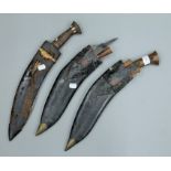 A bone inset wooden handled kukri in scabbard and two other kukris. The former 46.5 cm long.