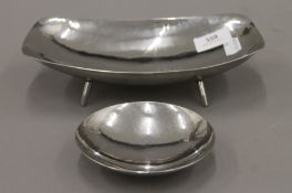 Two Keswick School of Industrial Art beaten white metal dishes. The largest 23 cm long.