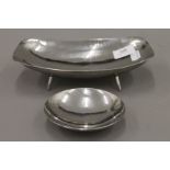 Two Keswick School of Industrial Art beaten white metal dishes. The largest 23 cm long.