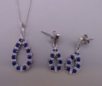 A silver pendant and matching earrings.