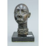 An antique bronze bust of a young girl, probably Nigerian, mounted on a wooden stand.