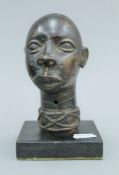 An antique bronze bust of a young girl, probably Nigerian, mounted on a wooden stand.