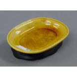 An Oriental yellow porcelain dish, with stand. 11.5 cm long.