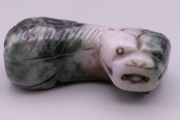 A Chinese russet green jade toggle in the form of a recumbent dog of fo. 4.5 cm long.