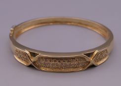 A 14 ct gold diamond set bangle form bracelet. 6.5 cm wide. 23.8 grammes total weight.