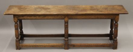 An oak bench stool. 137 cm long, 30.5 cm deep, 45 cm high.