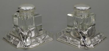 A pair of glass and silver plated inkwells, the bases surmounted with a fox mask, saddle and whip.