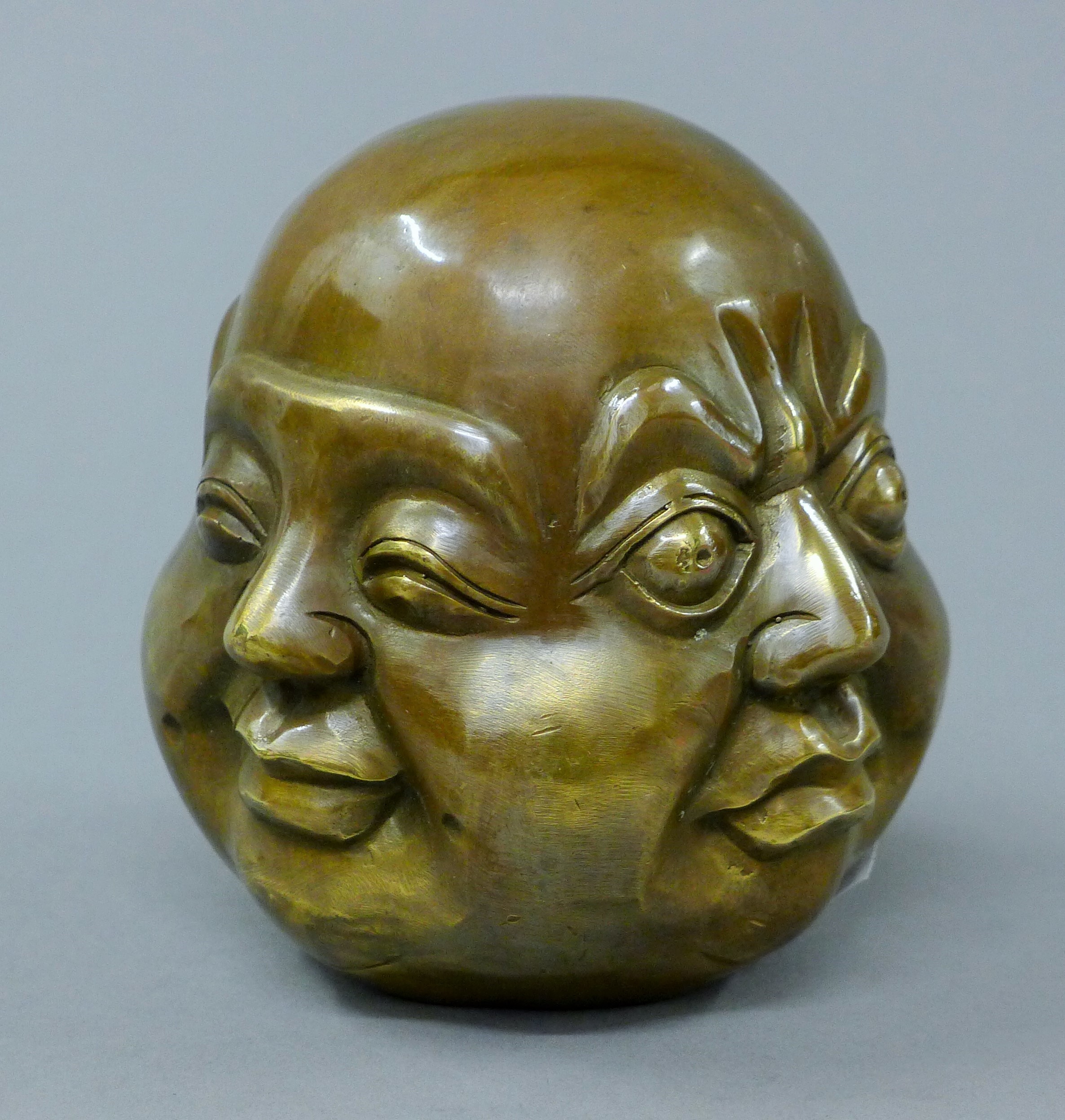 A brass four faced buddha head. 10.5 cm high.