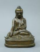 An antique bronze model of a seated buddha with glass inset eyes. 15.5 cm high.