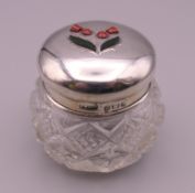 A hardstone inset thistle motif silver topped glass jar. 5 cm high.