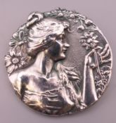 An Art Nouveau style brooch depicting a girl holding a flower. 4.5 cm diameter.