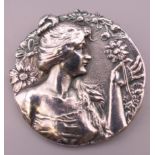 An Art Nouveau style brooch depicting a girl holding a flower. 4.5 cm diameter.