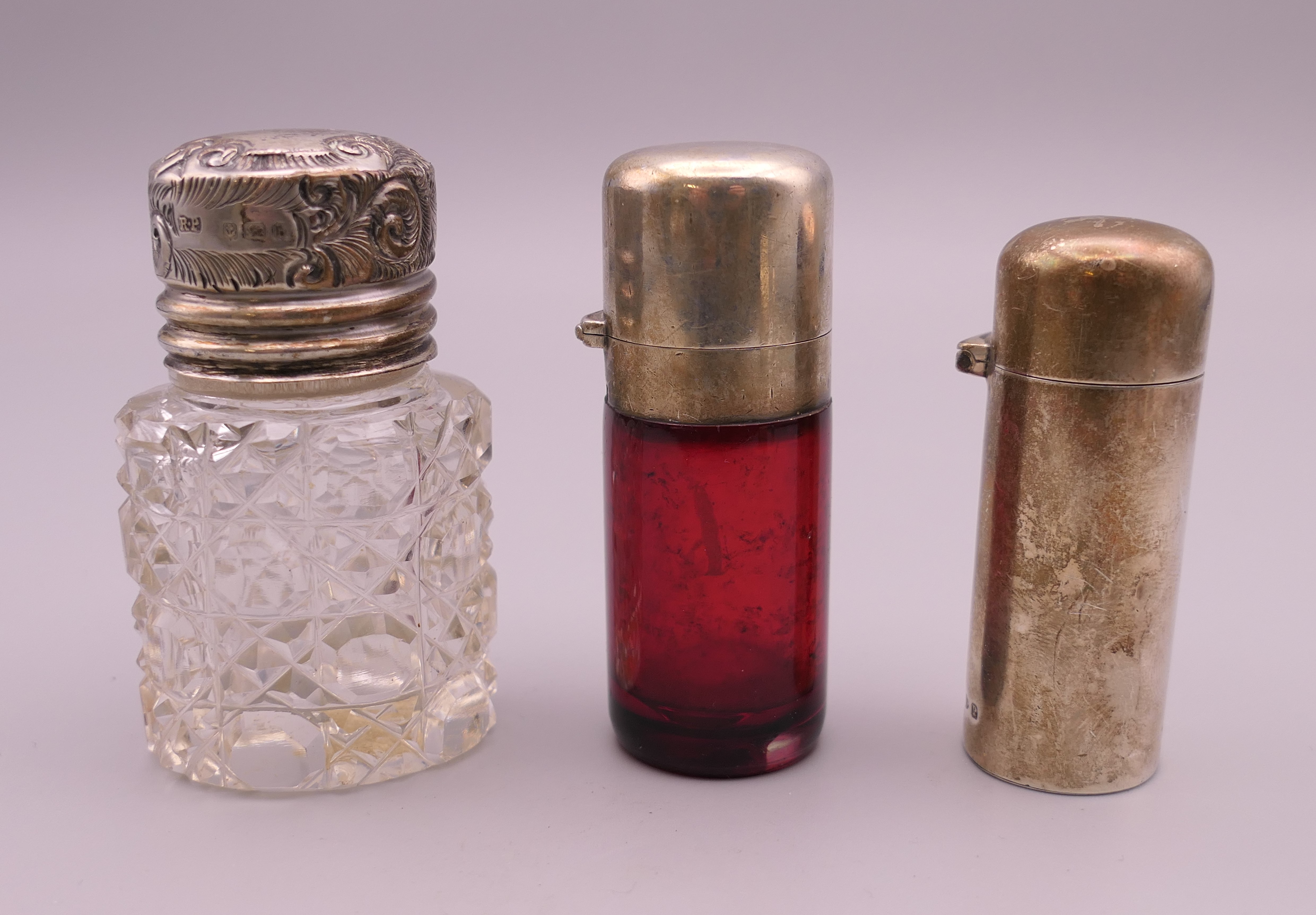 A silver clad scent bottle and two silver lid bottles. Tallest 6.25 cm high.