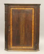 A George III oak and mahogany corner cupboard. 85 cm wide.