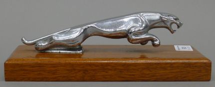 A vintage Jaguar car mascot, the chromed figure now fitted to a mahogany base. 23 cm long overall.