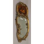 A 19th century gilt wall glass surmounted with a cherub and with inset painted panel depicting a