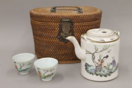 A late 19th/early 20th century Chinese teapot and two tea bowls, housed in a basket.