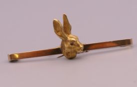 A 9 ct gold bar brooch centred with a hare. 5.5 cm long. 6.8 grammes total weight.