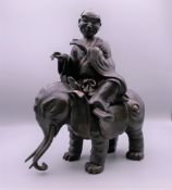 A Chinese bronze model of a gentleman seated on an elephant. 23.5 cm high.