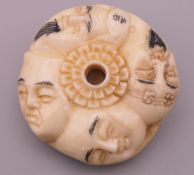 A bone carved netsuke depicting faces. 4 cm diameter.