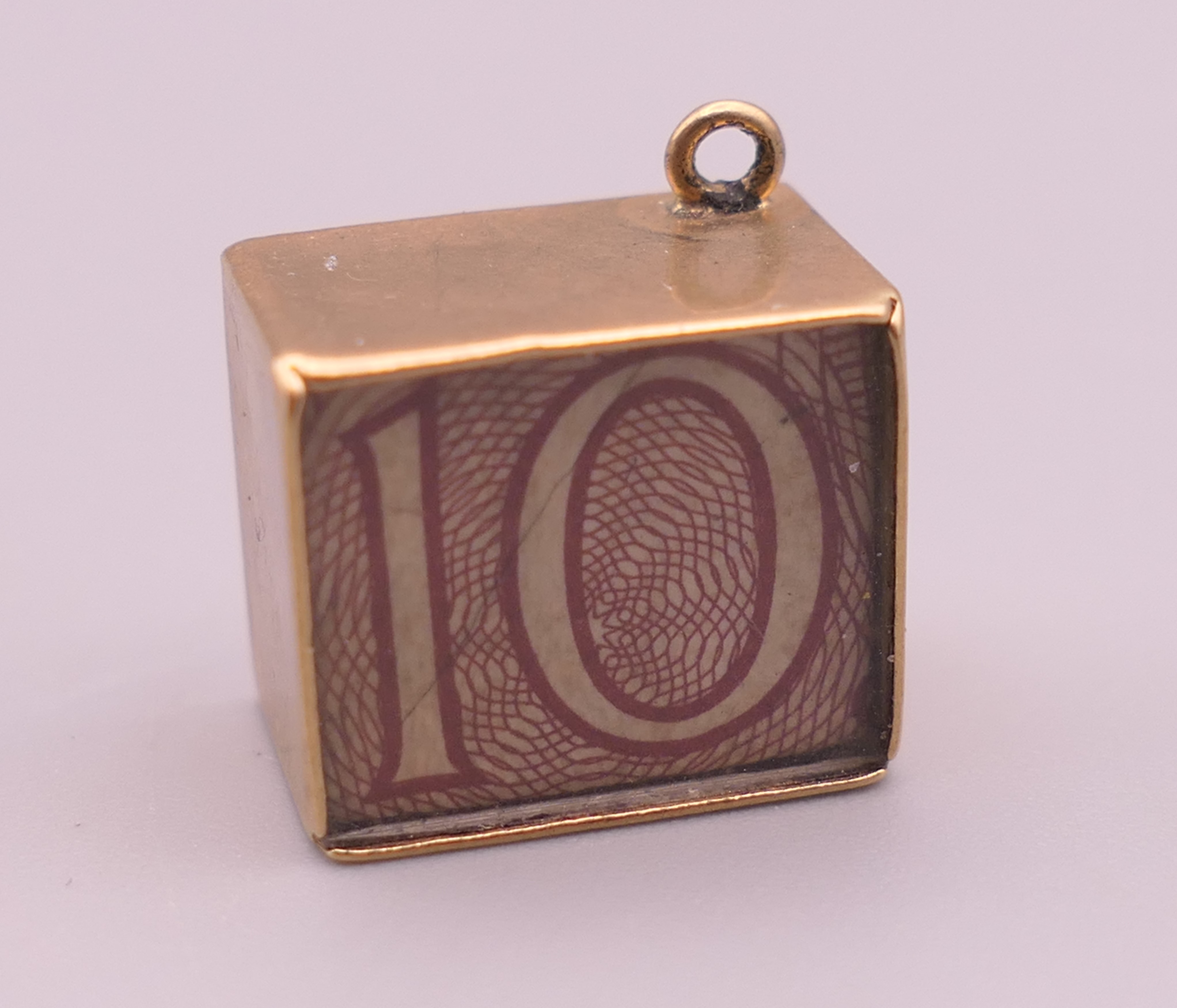 A 9 ct gold emergency ten shilling note charm. 1.3 cm high. 2.5 grammes total weight.