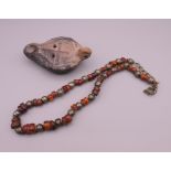 An amber and white metal bead necklace and a terracotta oil lamp.