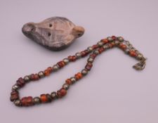 An amber and white metal bead necklace and a terracotta oil lamp.