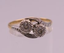 An 18 ct gold two stone diamond crossover ring. Ring size N/O. 2.7 grammes total weight.