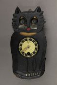 A small early 20th century carved wooden clock formed as a cat with moving eyes. 15 cm high.