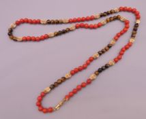 A 14 K gold, coral and tigers eye necklace. Approximately 66 cm long.