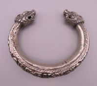 A 19th century Chinese unmarked silver bangle with dragon's head. 9 cm wide.