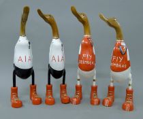 Four wooden ducks in boots; two in Arsenal colours and two in Tottenham colours.
