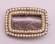 A 19th century unmarked gold seed pearl mounted hair plait mourning brooch,
