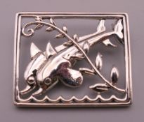 A silver dolphin form brooch. Approximately 3 cm x 3.5 cm.