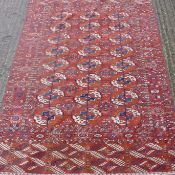 A red ground Afghan elephant foot pattern rug. 205 x 114 cm.