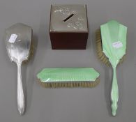 A silver top money box, a silver brush and two other brushes. The former 7.5 cm high.