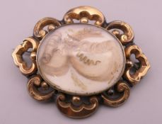 An antique gilt metal and seed pearl mourning brooch. 4.6 cm wide. 11.1 grammes total weight.