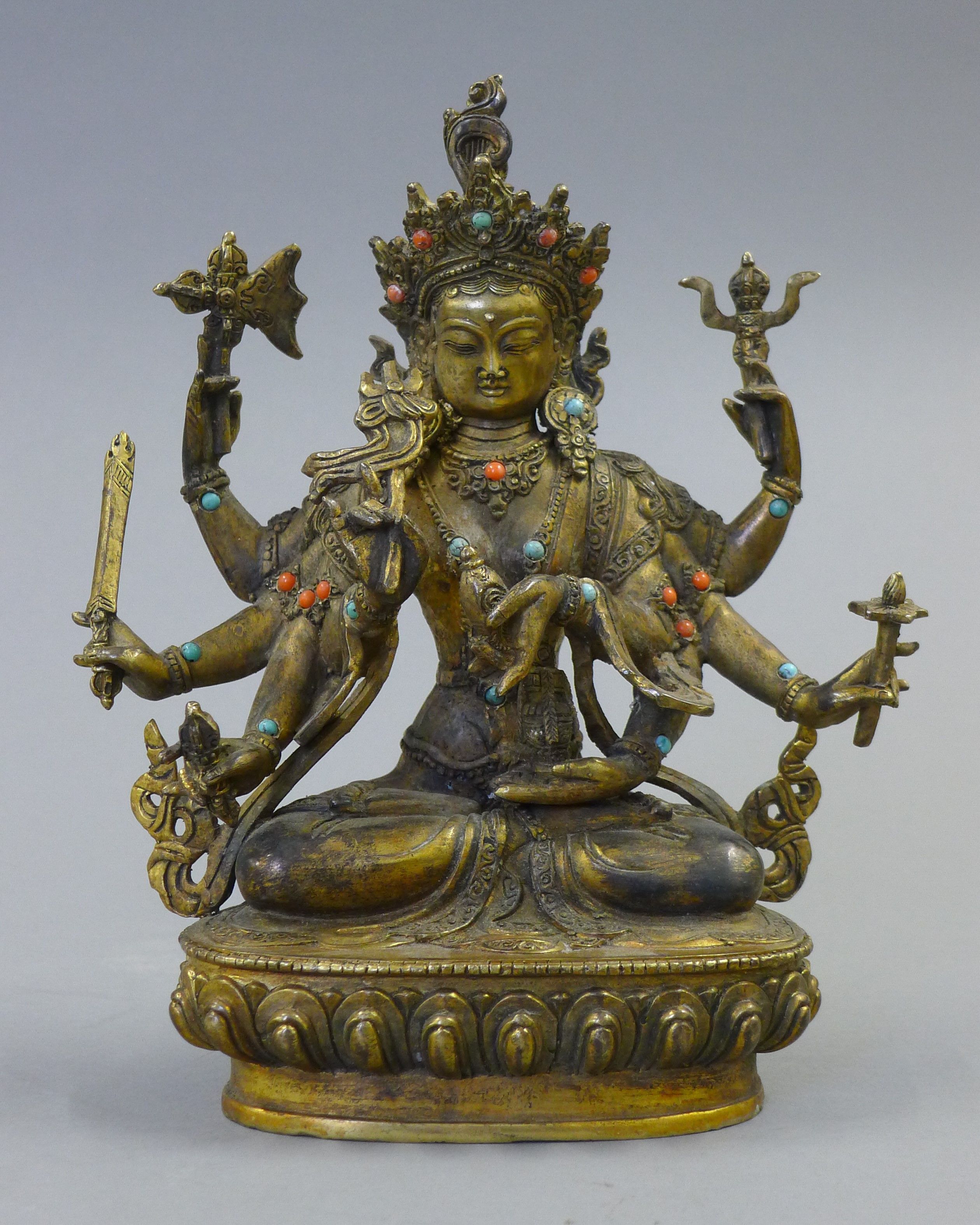 A gilt bronze model of a deity decorated with coral and turquoise. 21.5 cm high.