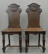 A pair of Victorian carved oak hall chairs. 48 cm wide.